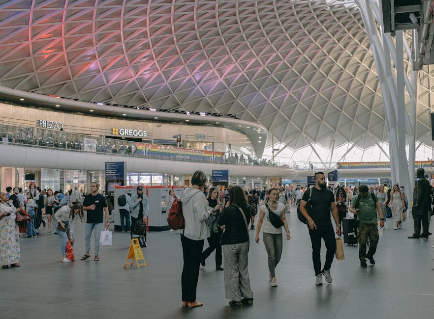 A detailed view of a large, modern architectural ceiling composed of a complex grid of white, metallic structural beams arranged in a repeating diamond pattern. The beams intersect to form a series of